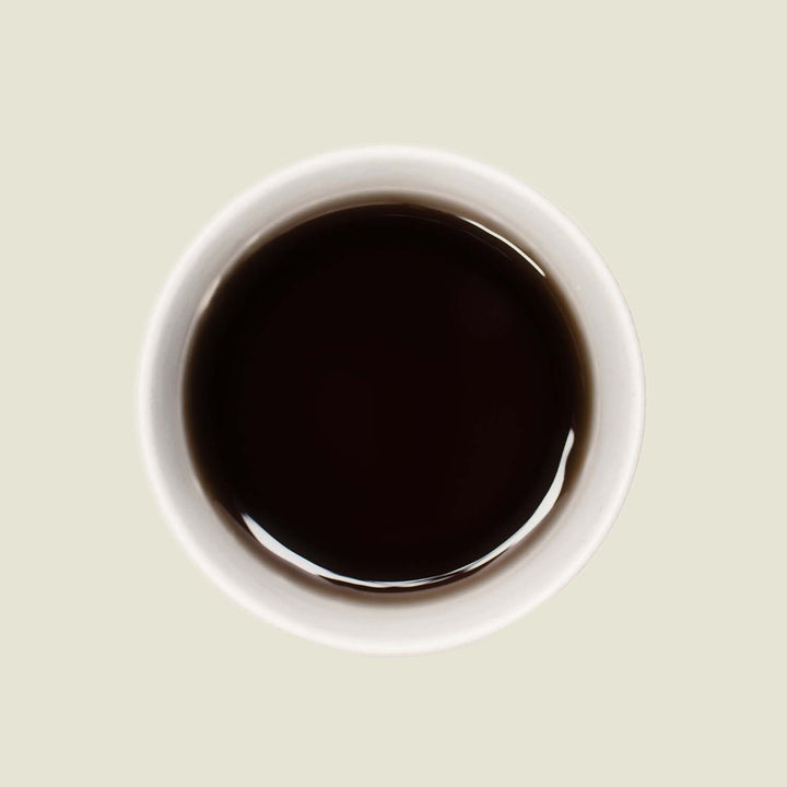 Tasse Keemun OP von oben, mit einer tiefen, goldbraunen Teefarbe, die die charakteristische Komplexität und milden Aromen dieses Schwarztees widerspiegelt.
Keemun OP cup from above, displaying a rich, golden-brown tea color that reflects the characteristic complexity and mild flavors of this black tea.