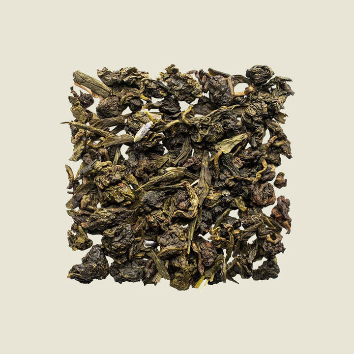 Lose aufgelegte Oolong Lavandula-Teeblätter von oben fotografiert, sanft gedrehte Blätter mit Lavendel-Elementen – floraler Tee von Noema.