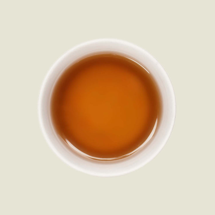 Tasse Oolong Lavandula von oben, mit einer goldenen bis bernsteinfarbenen Teefarbe, die die beruhigenden Aromen von Oolong und Lavendel widerspiegelt.
Oolong Lavandula cup from above, with a golden to amber tea color that reflects the soothing aromas of Oolong and lavender.