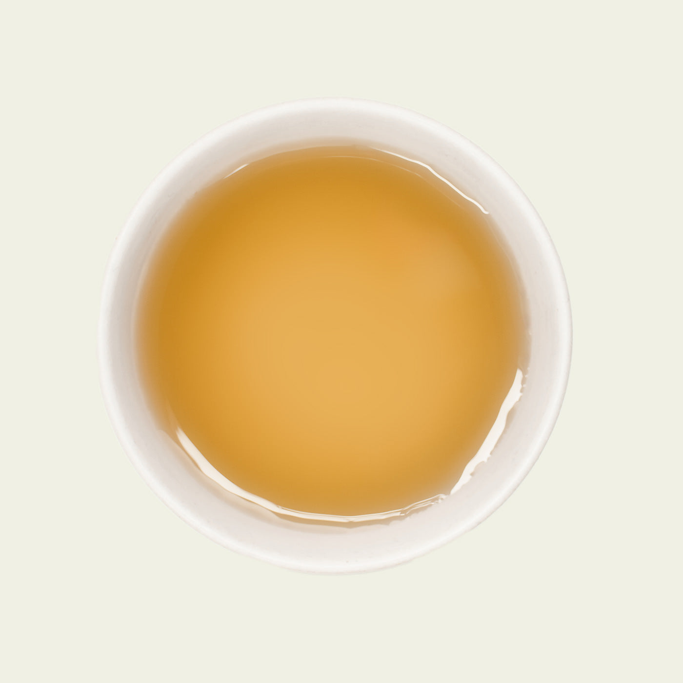 Mao Feng Tee – Von oben fotografiert, der helle goldene Tee in einer weißen Porzellantasse, mit klarer Tassenfarbe und weichen Reflexionen.