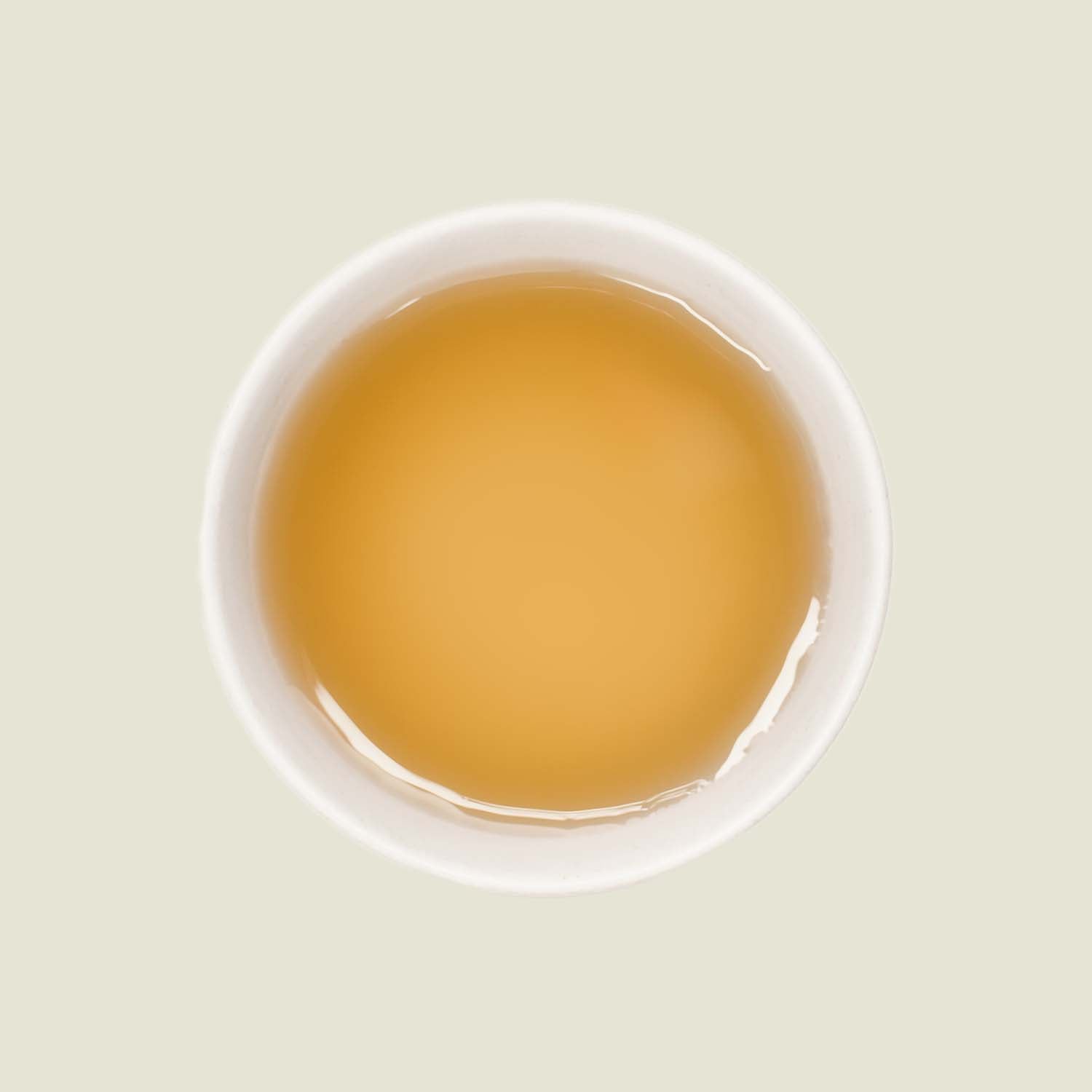 Mao Feng Tee – Von oben fotografiert, der helle goldene Tee in einer weißen Porzellantasse, mit klarer Tassenfarbe und weichen Reflexionen.