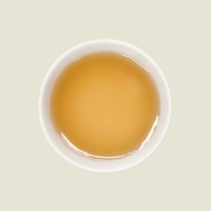 Mao Feng Tee – Von oben fotografiert, der helle goldene Tee in einer weißen Porzellantasse, mit klarer Tassenfarbe und weichen Reflexionen.