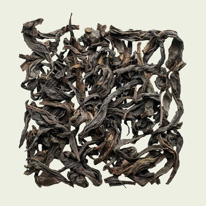 Flach fotografierte Da Hong Pao-Blätter, dunkel geröstet und leicht verdreht – intensiver Wuyi-Oolong von Noema.