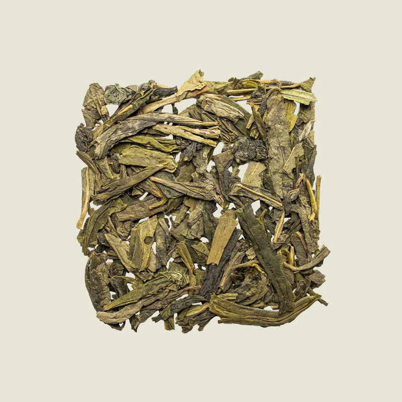 Lung Ching Teeblätter flach gepresst, lose aufgelegt in Draufsicht – chinesischer Klassiker mit nussigem Charakter.