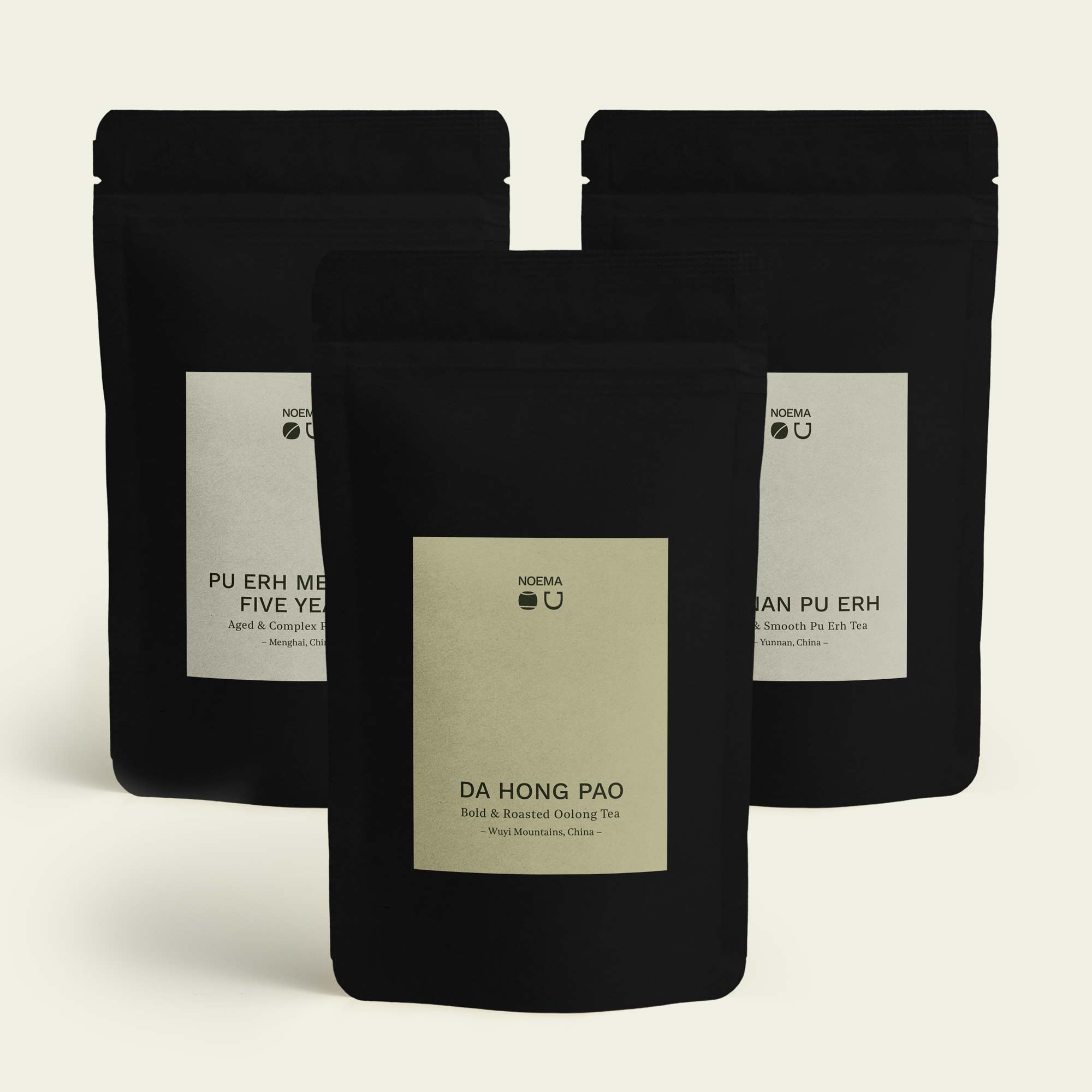Noema Tee Probierpaket ‘Erdung & Tiefe’ mit Da Hong Pao im Vordergrund und Yunnan Pu Erh sowie Pu Erh Menghai Five Years im Hintergrund.