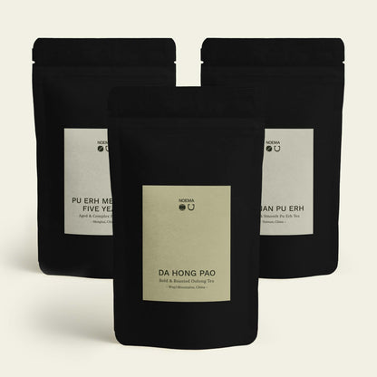 Noema Tee Probierpaket ‘Erdung & Tiefe’ mit Da Hong Pao im Vordergrund und Yunnan Pu Erh sowie Pu Erh Menghai Five Years im Hintergrund.