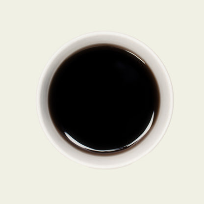 Tasse Pu Erh Menghai Five Years von oben, mit einer tiefen, rotbraunen Teefarbe, die die lang gereiften, komplexen Aromen dieses Tees widerspiegelt.

Pu Erh Menghai Five Years cup from above, showcasing the deep reddish-brown tea color that reflects the long-aged, complex flavors of this tea.