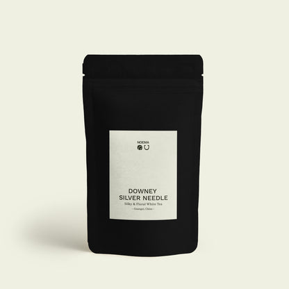 Verpackung des Downey Silver Needle Tees mit Etikett, abgebildet vor einem schlichten Hintergrund, der die filigrane Eleganz und blumige Süße dieses hochwertigen weißen Tees unterstreicht.

Packaging of Downey Silver Needle Tea with label, displayed against a simple background that highlights the delicate elegance and floral sweetness of this premium white tea.