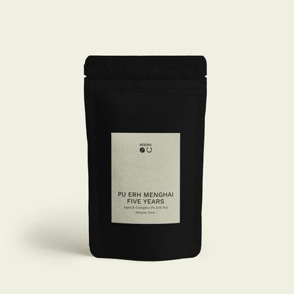Verpackung des Pu Erh Menghai Five Years Tees mit Etikett, abgebildet vor einem schlichten Hintergrund, der die reiche Tiefe und die lang gereifte Aromen dieses Tees widerspiegelt.

Packaging of Pu Erh Menghai Five Years Tea with label, displayed against a simple background that reflects the rich depth and long-aged flavors of this tea.