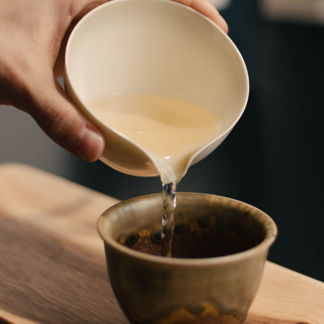 Gelber Tee Huang Ya wird in Tasse eingeschenkt