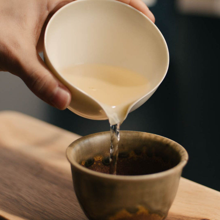 Gelber Tee Huang Ya wird in Tasse eingeschenkt